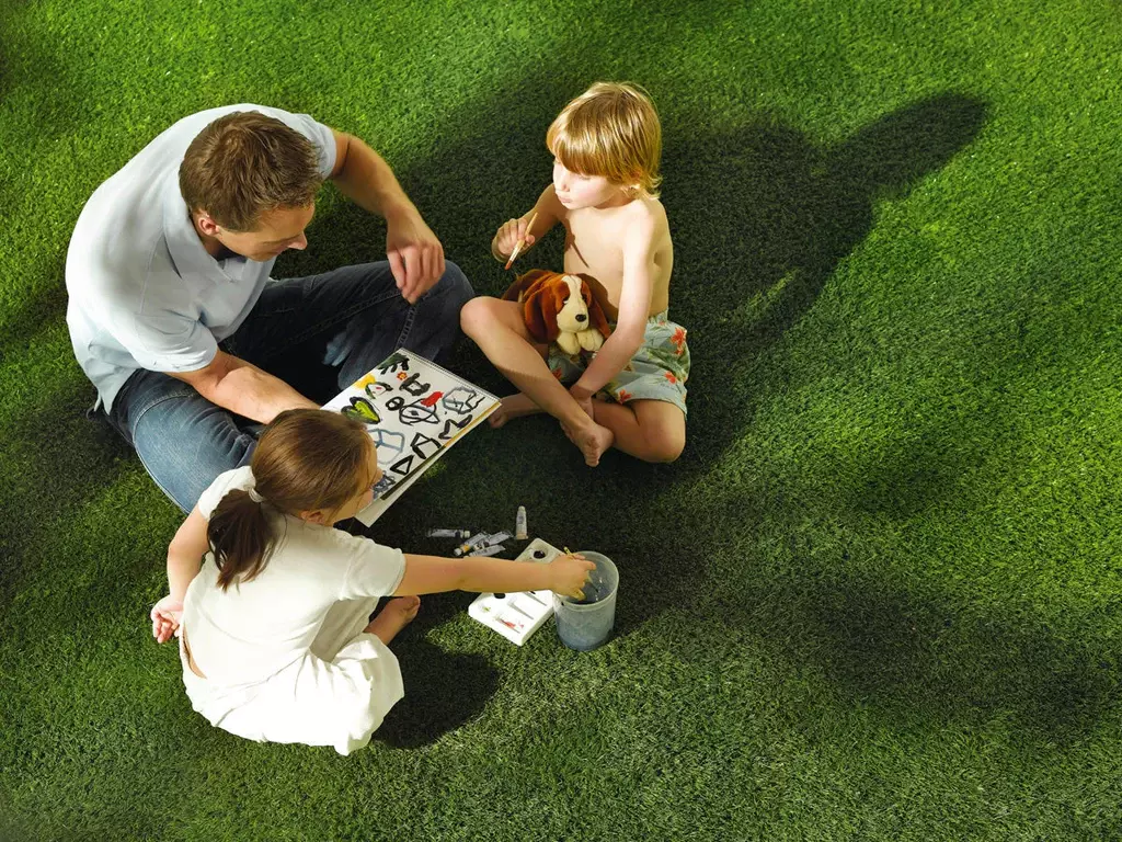 Father and children playing on synthetic grass lawn highlighting soft, safe artificial turf surface for landscaping and family outdoor use