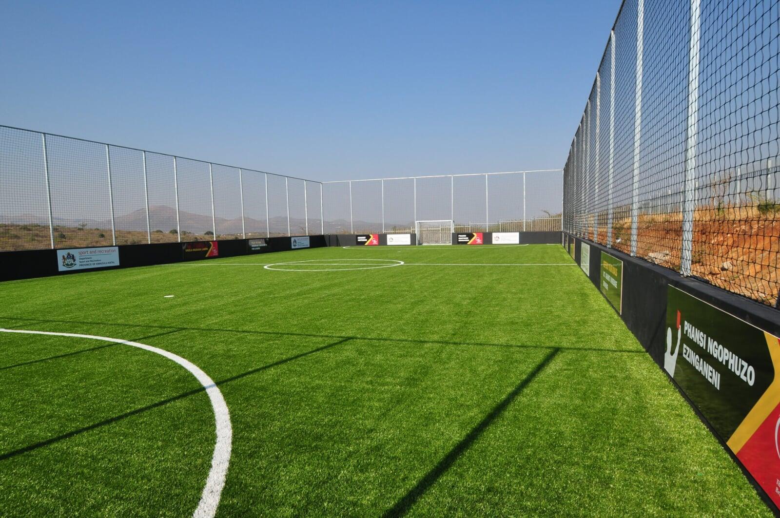 Football field with premium artificial turf and boundary fencing, showcasing durable synthetic grass for high-performance sports applications Football field with premium artificial turf and boundary fencing, showcasing durable synthetic grass for high-performance sports applications