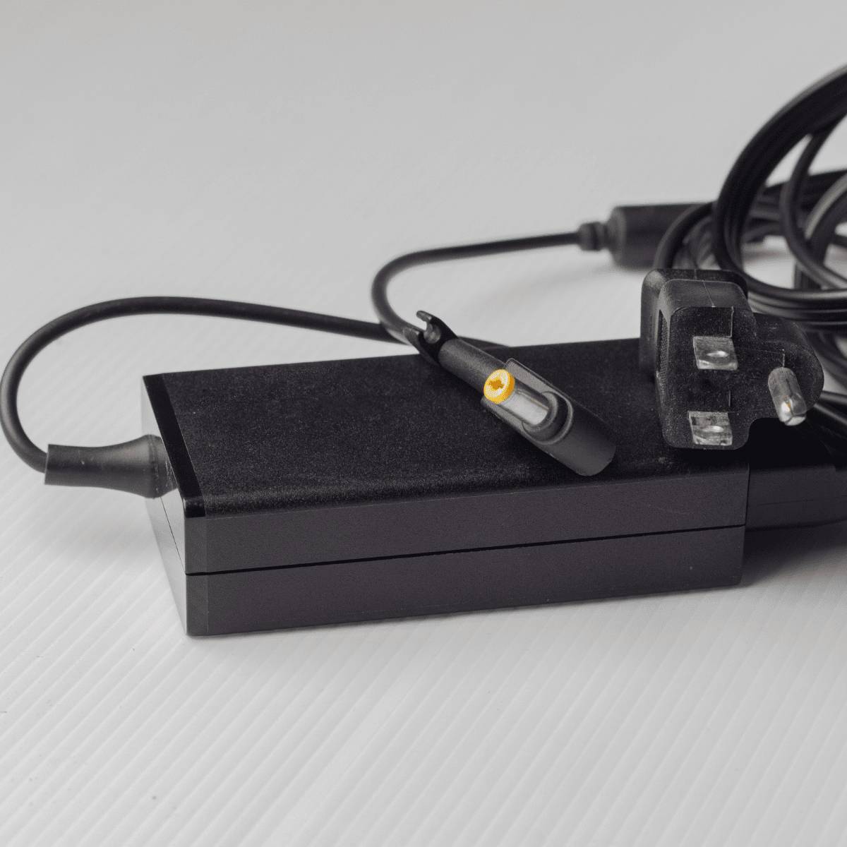 "Black laptop adapter with a compact design, featuring a power input for wall sockets and an output cable for charging laptops efficiently." "Black laptop adapter with a compact design, featuring a power input for wall sockets and an output cable for charging laptops efficiently."