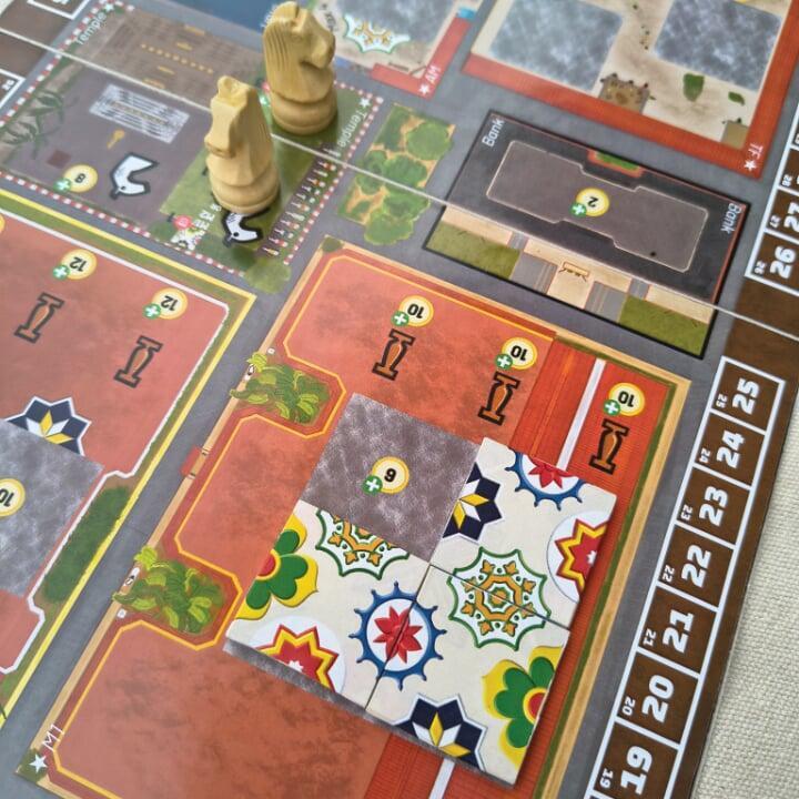 Boardgame with colourful patterned tiles and white chess knights placed on the board. Boardgame with colourful patterned tiles and white chess knights placed on the board.