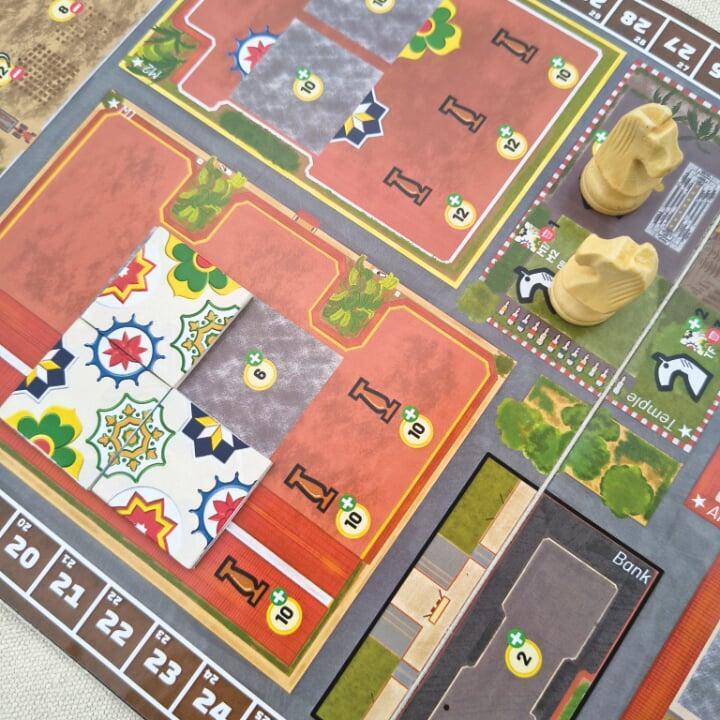 Boardgame with colourful tiles with patterns placed on it. A chess knight is also visible on the board.