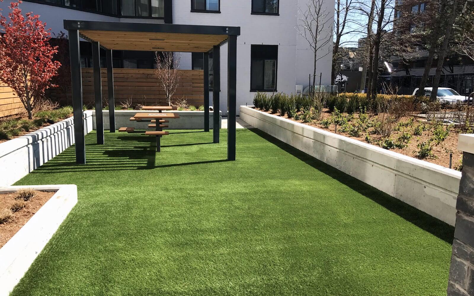 Residential courtyard with artificial turf flooring and pergola seating, showcasing durable synthetic grass for modern landscaping spaces