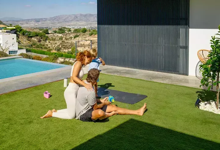 Family relaxing on premium artificial turf lawn near pool, showcasing durable synthetic grass for landscaping and outdoor living spaces Family relaxing on premium artificial turf lawn near pool, showcasing durable synthetic grass for landscaping and outdoor living spaces