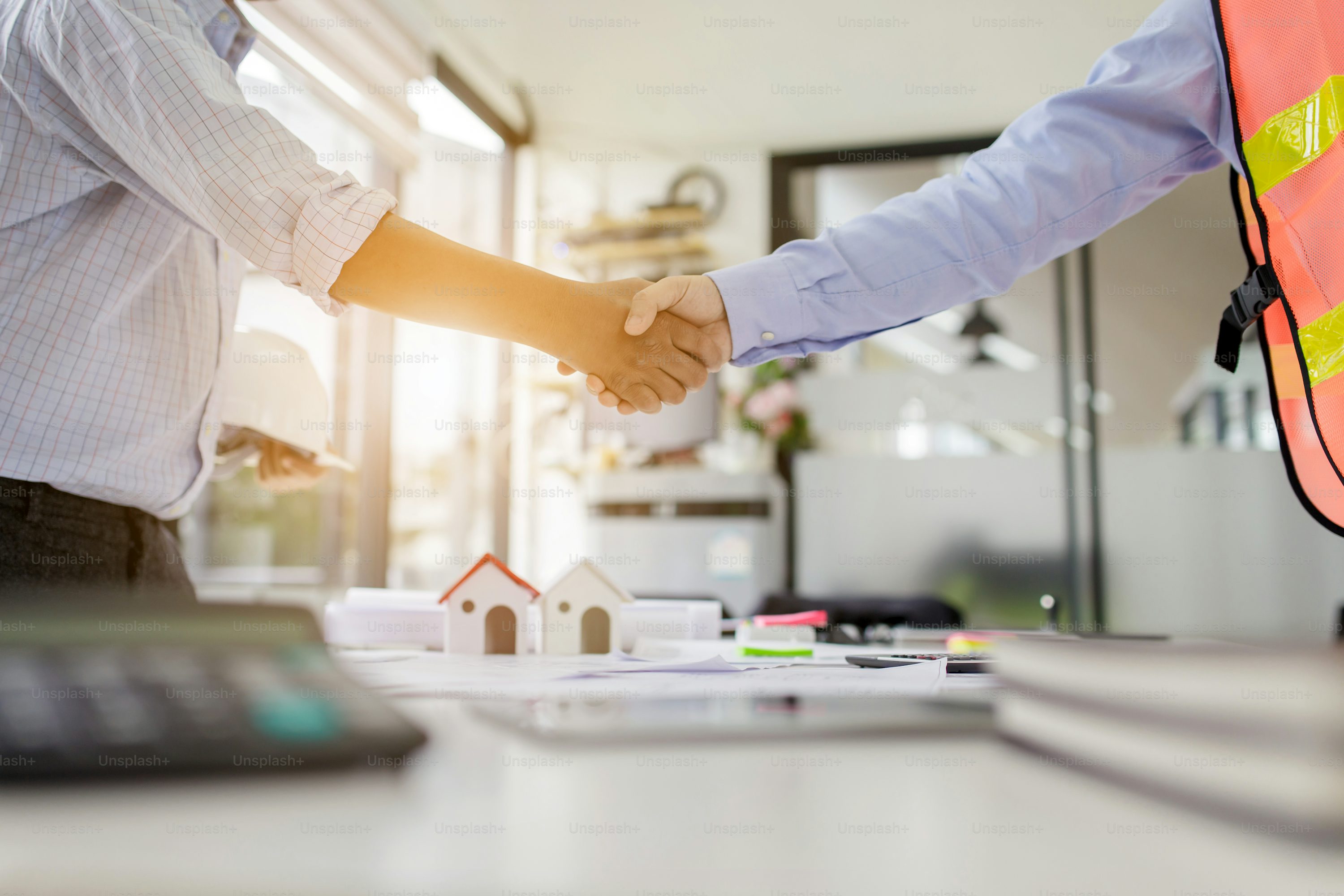 Real estate deal handshake with blueprint on desk – Homizon property and construction consultation