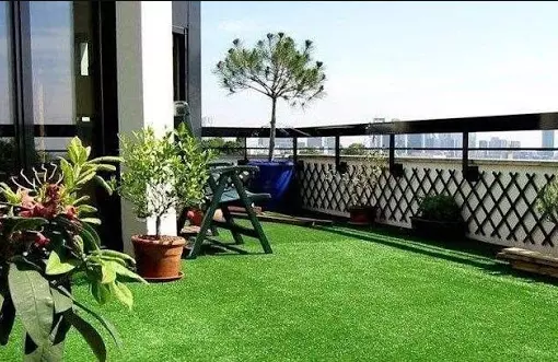 Rooftop garden with synthetic grass flooring, potted plants and seating area, showcasing durable artificial turf for modern landscaping spaces Rooftop garden with synthetic grass flooring, potted plants and seating area, showcasing durable artificial turf for modern landscaping spaces