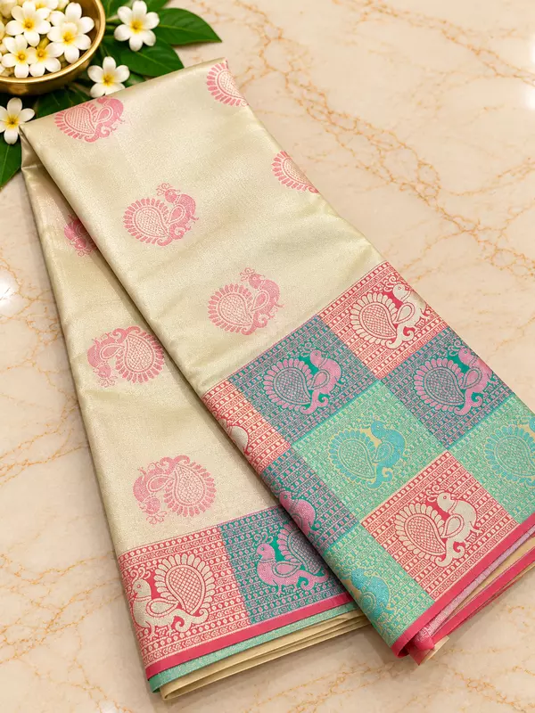 stunning ivory-gold Tissue Silk Saree featuring delicate pink paisley motifs beautifully scattered across the body.