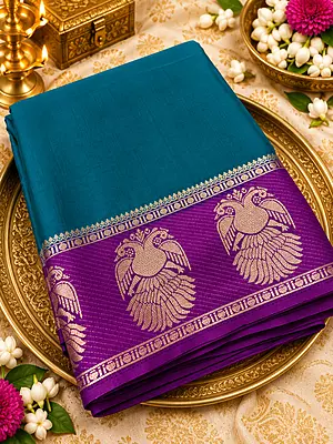 ? ROYAL PURPLE SILK SAREE A stunning royal purple silk saree featuring intricate gold zari weaving, elegant peacock motifs, and a beautifully detailed geometric floral pattern.