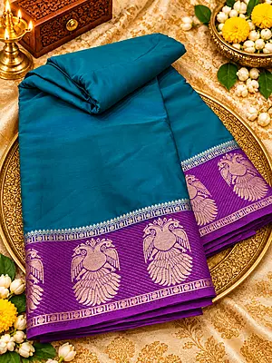 ? ROYAL PURPLE SILK SAREE A stunning royal purple silk saree featuring intricate gold zari weaving, elegant peacock motifs, and a beautifully detailed geometric floral pattern.