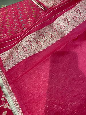 A gorgeous rani pink silk saree featuring an all-over delicate woven vine and floral creeper pattern in shimmering silver and pastel threads.