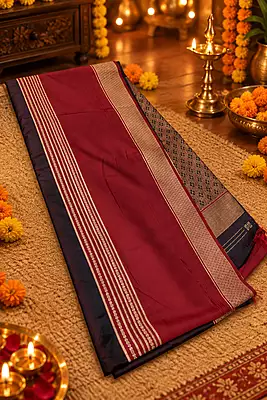 A rich and elegant deep maroon silk saree featuring beautiful traditional zari detailing. The saree is enhanced with fine golden striped borders