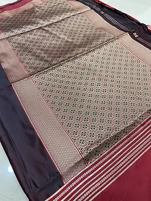 A rich and elegant deep maroon silk saree featuring beautiful traditional zari detailing. The saree is enhanced with fine golden striped borders