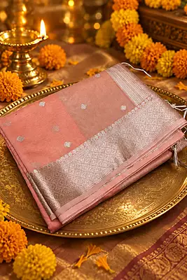 A delicate and elegant peach pink silk saree featuring a subtle tissue-like sheen and beautifully woven silver zari diamond buttas throughout the body.