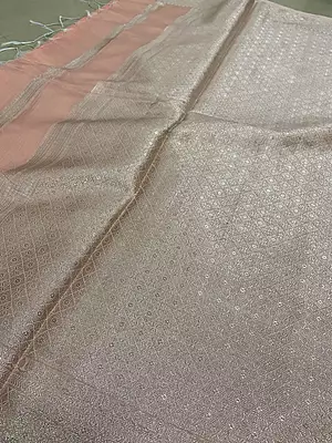 A delicate and elegant peach pink silk saree featuring a subtle tissue-like sheen and beautifully woven silver zari diamond buttas throughout the body.