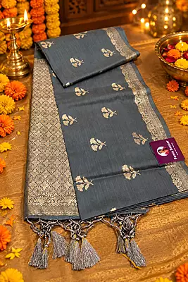 A sophisticated slate grey silk saree featuring delicate silver zari floral buttas scattered beautifully across the body.