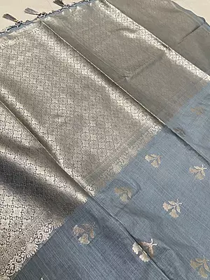 A sophisticated slate grey silk saree featuring delicate silver zari floral buttas scattered beautifully across the body.