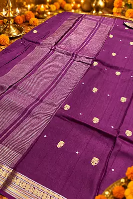 A rich deep purple silk saree featuring elegant gold zari motifs and tiny silver-toned buttas scattered across the body.