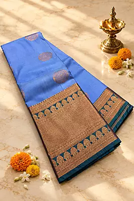 A graceful powder blue silk saree featuring elegant antique-gold paisley motifs scattered across the body.