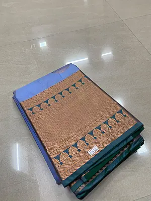 A graceful powder blue silk saree featuring elegant antique-gold paisley motifs scattered across the body.