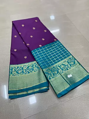 A gorgeous deep purple silk saree featuring delicate gold zari buttas scattered elegantly across the body.