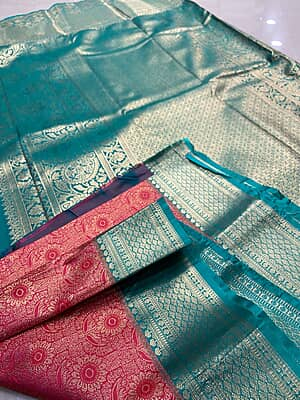 A rich red and teal silk saree featuring an intricate all-over gold zari floral pattern on the body.