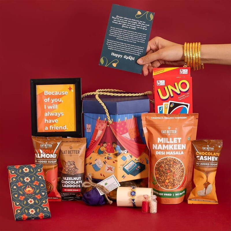 EAT BETTER CO Yaadon Ka Dabba 10-Item Rakhi Gift Hamper Evil Eye Rakhi, Chocolate Coated Almonds, Hazelnut Dry-Fruit Laddoos, Uno & More |for Brother Rakhi Gift Combo Set