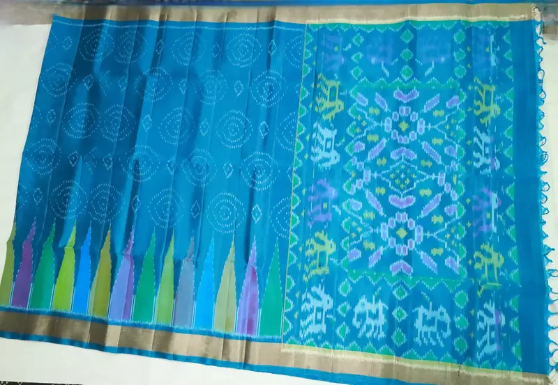 Teal blue silk saree with circular motifs, multicolour ikat pallu, and ikat blouse.