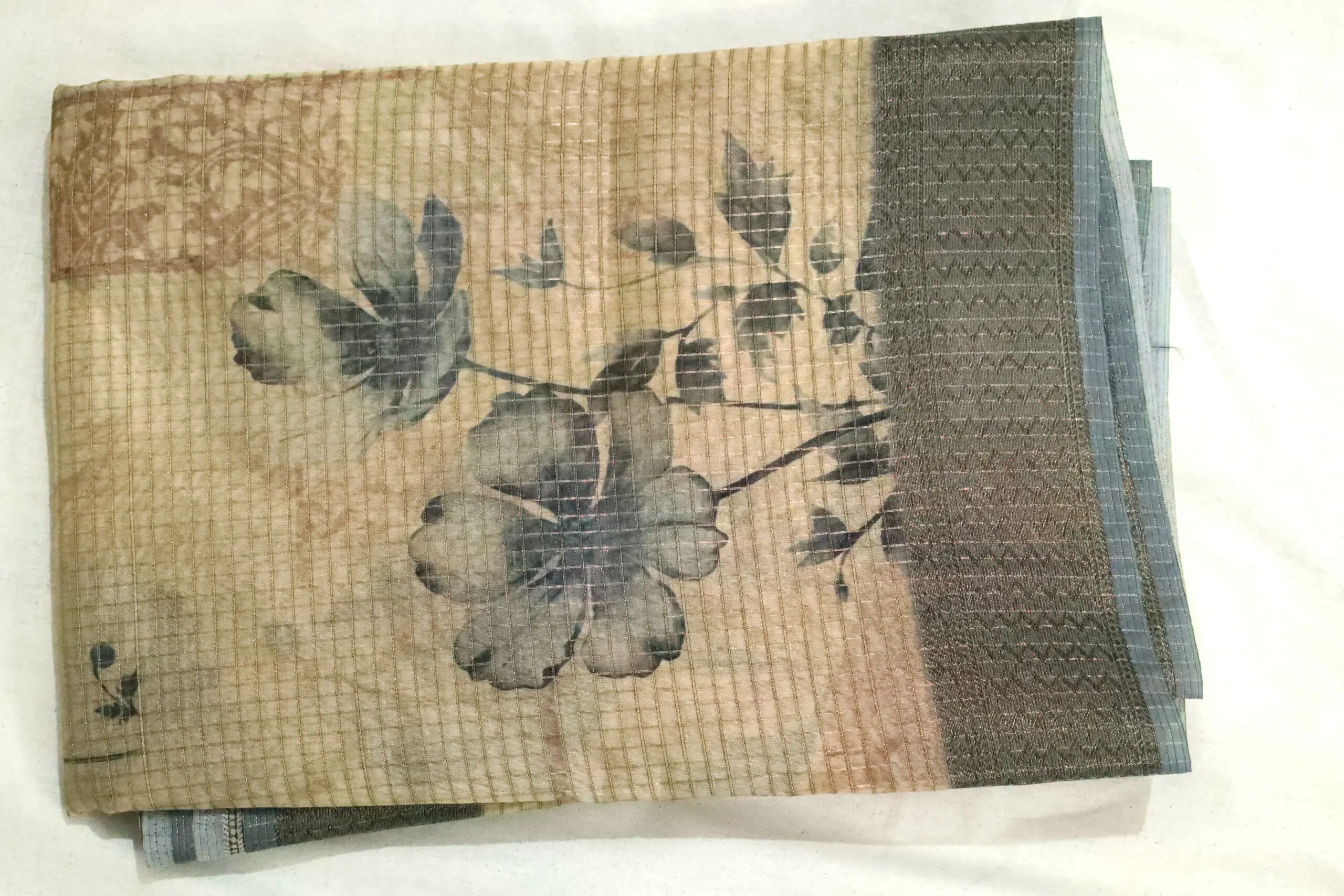 Elegant pastel green floral saree fabric with soft grid texture and shimmering zari border